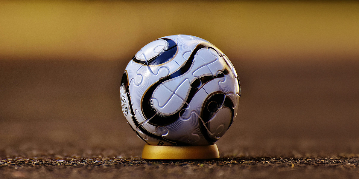 Image of a soccer ball against a gold colored soccer field