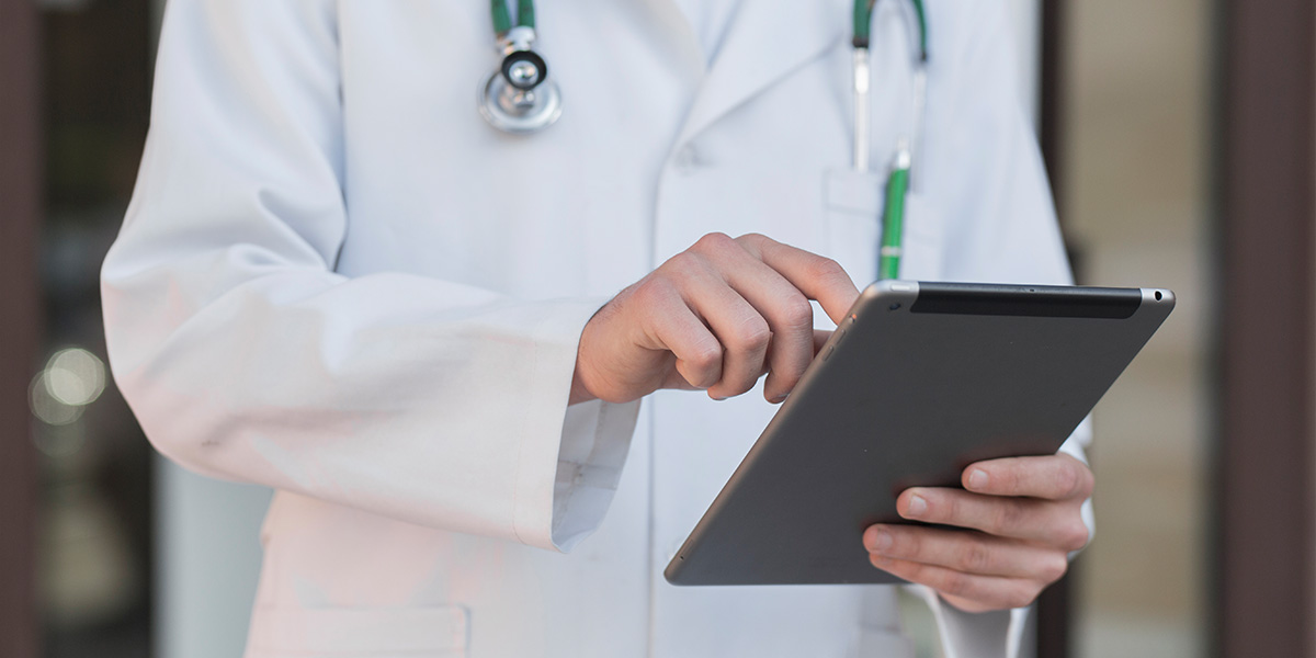 A zoomed in shot of a doctor in white robes, holding a tablet