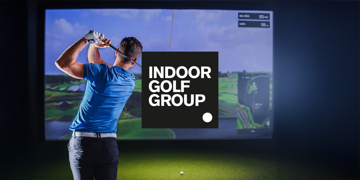 Indoor golf simulator with a man swinging his club. He is wearing a blue t-shirt. A logo for the Indoor Golf Group is in the center above the image.